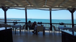 Faleza Balcic. Oameni la masă la o terasă ridicată pe picioare de lemn, deasupra mării. Foto cu telefonul: Călin Hera