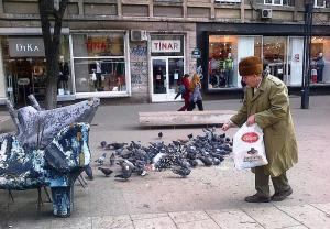 Vârstnic hrănind porumbei în Piaţa Romană, Bucureşti. Foto cu telefonul: Călin Hera